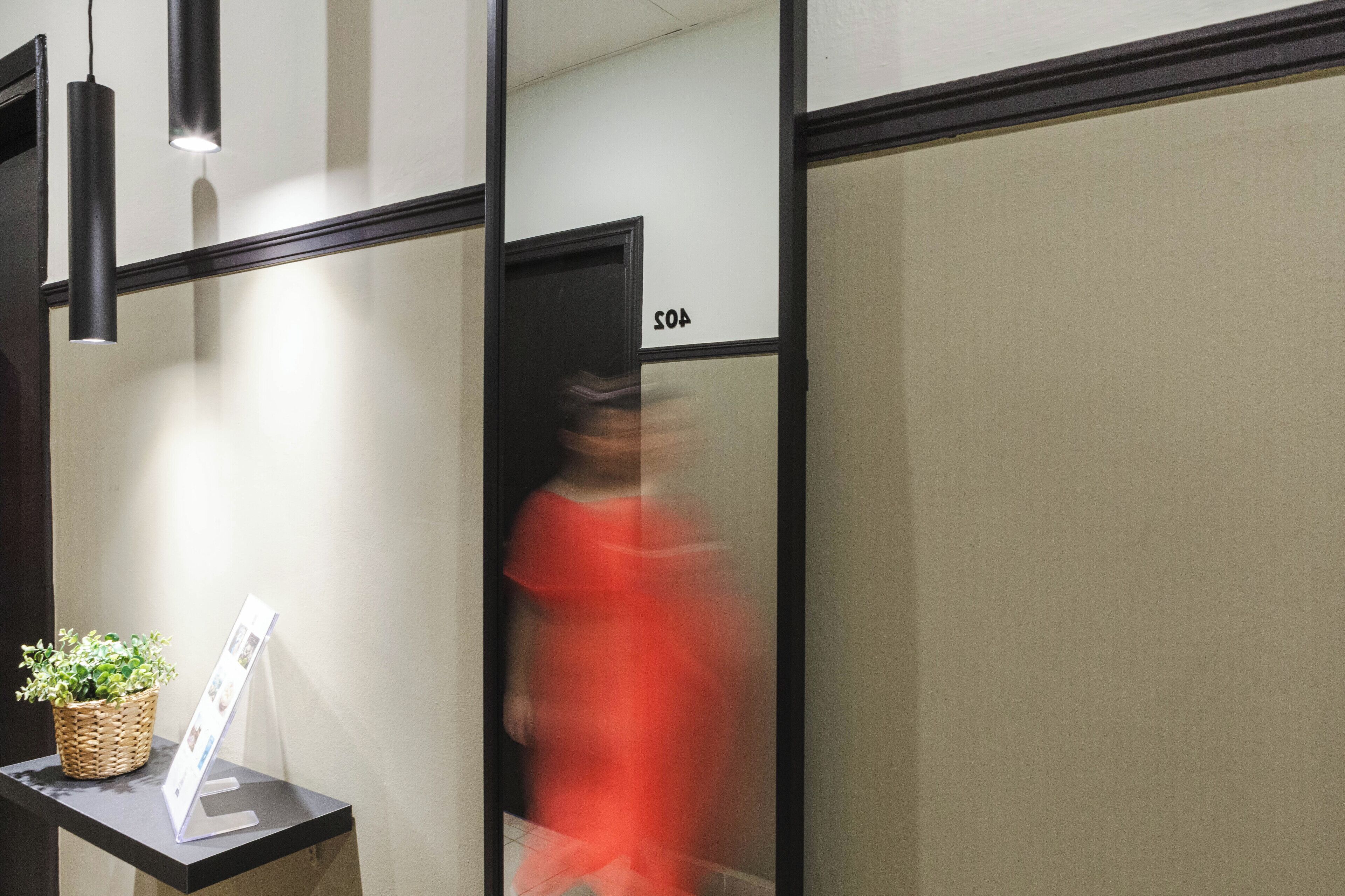 A hallway with a reception desk, a potted plant, and a sign.