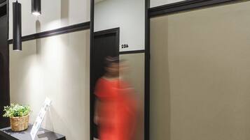 A hallway with a reception desk, a potted plant, and a sign.