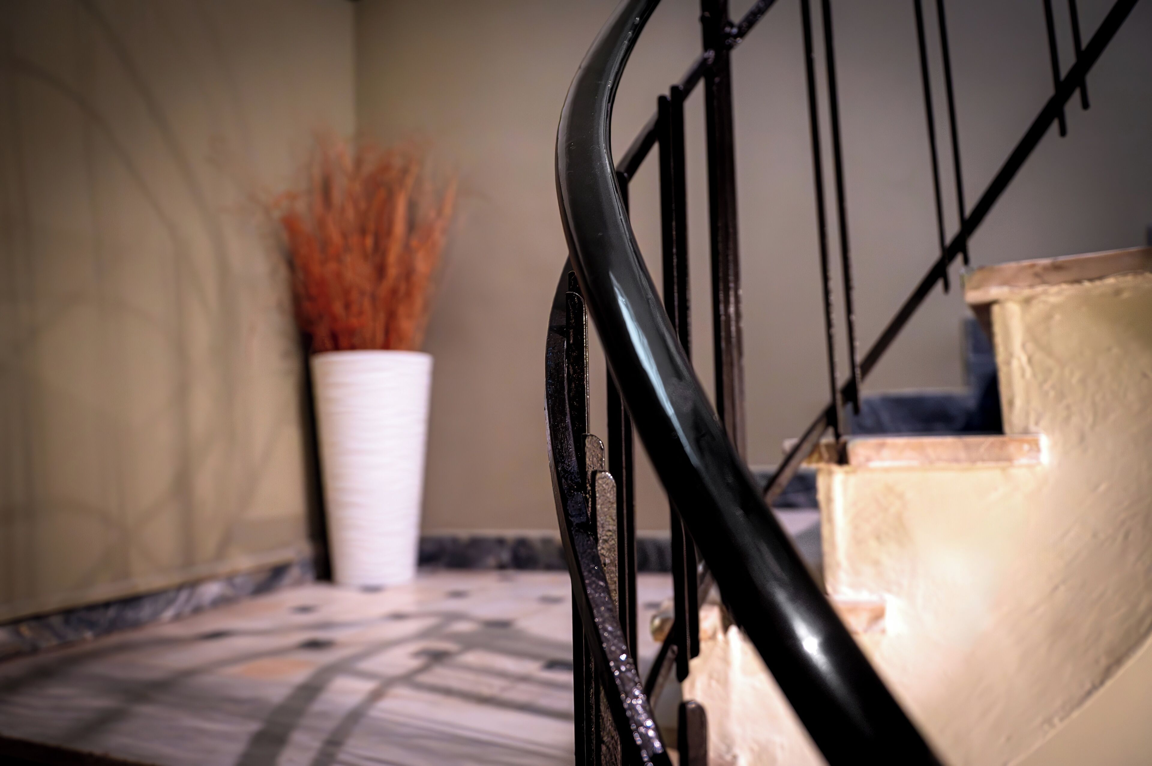 A staircase with a black handrail and beige steps.