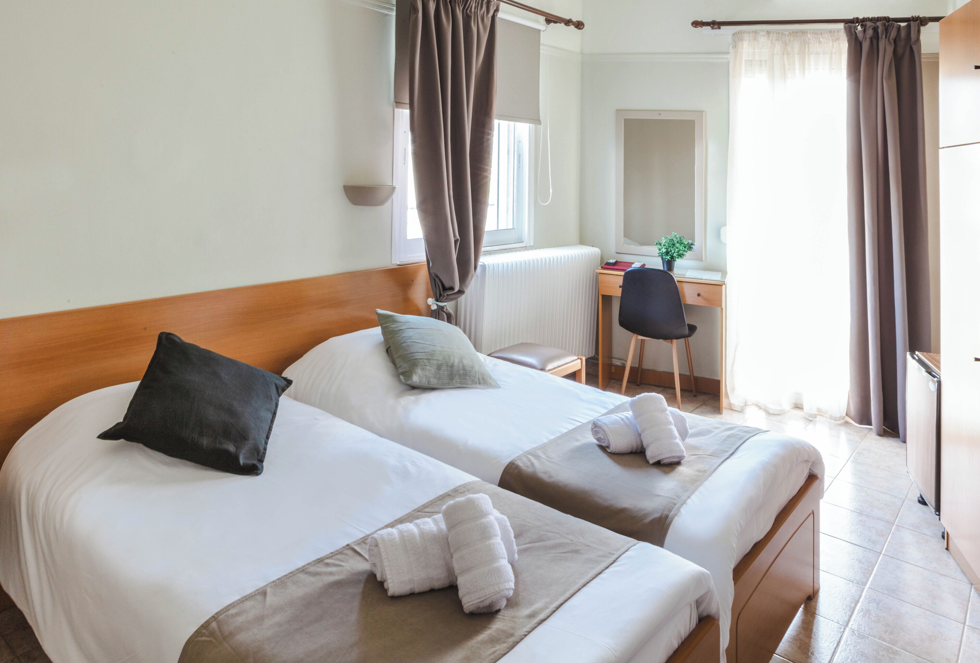 Ein Hotelzimmer mit zwei Betten, einem Schreibtisch, einem Stuhl und einem Spiegel.