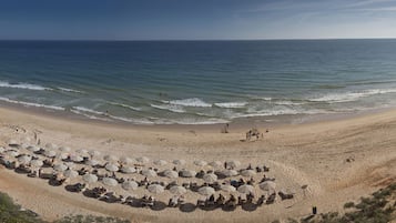 In StrandnĂ€he, weiĂer Sandstrand, Sonnenschirme, StrandtĂŒcher