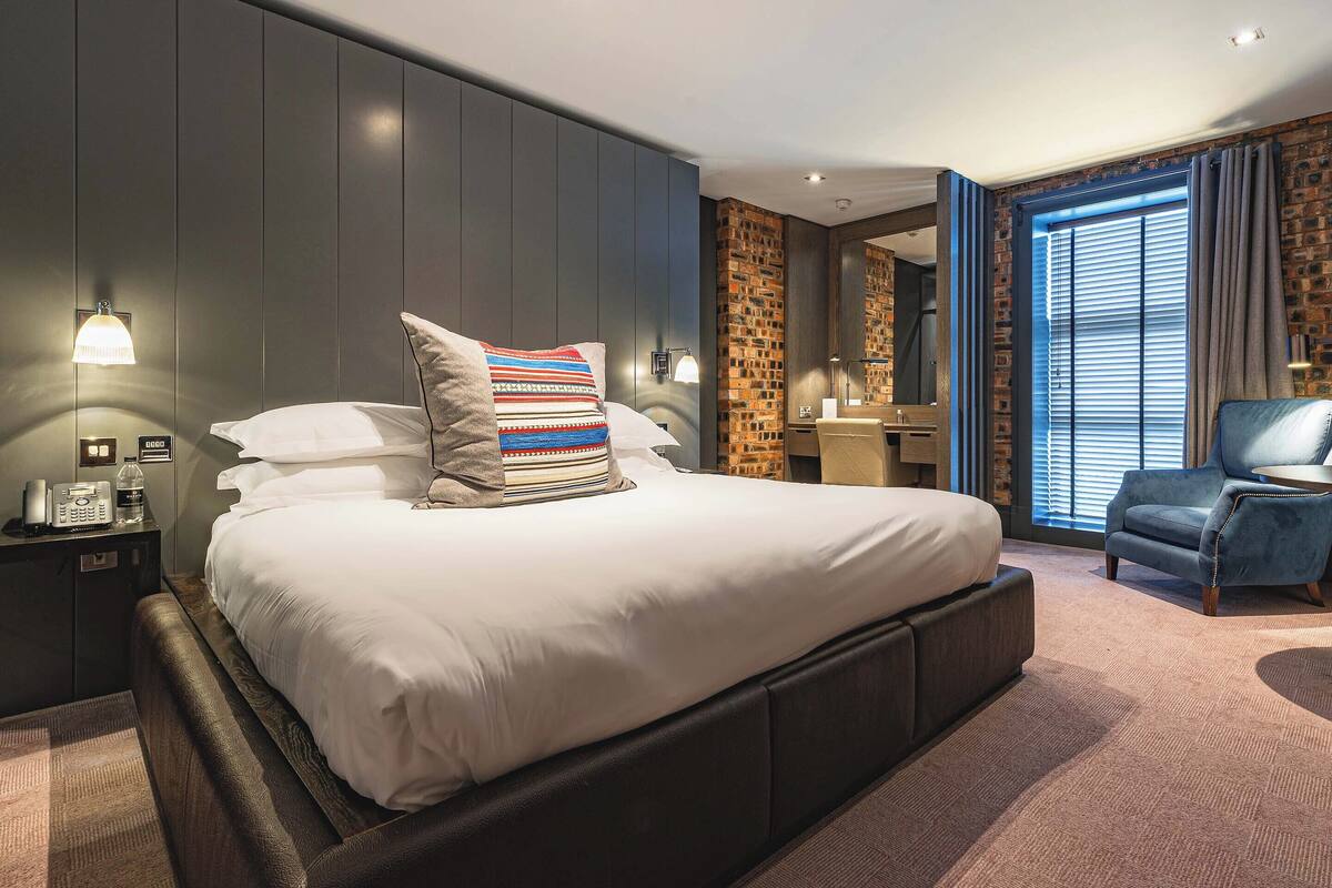 A modern hotel room with a large bed, a desk, and a chair.