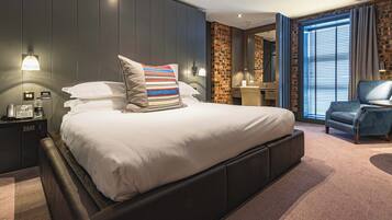 A modern hotel room with a large bed, a desk, and a chair.