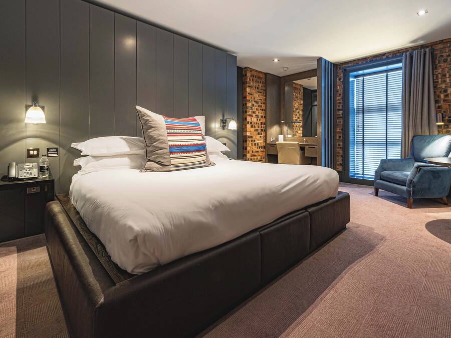 A modern hotel room with a large bed, a desk, and a chair.
