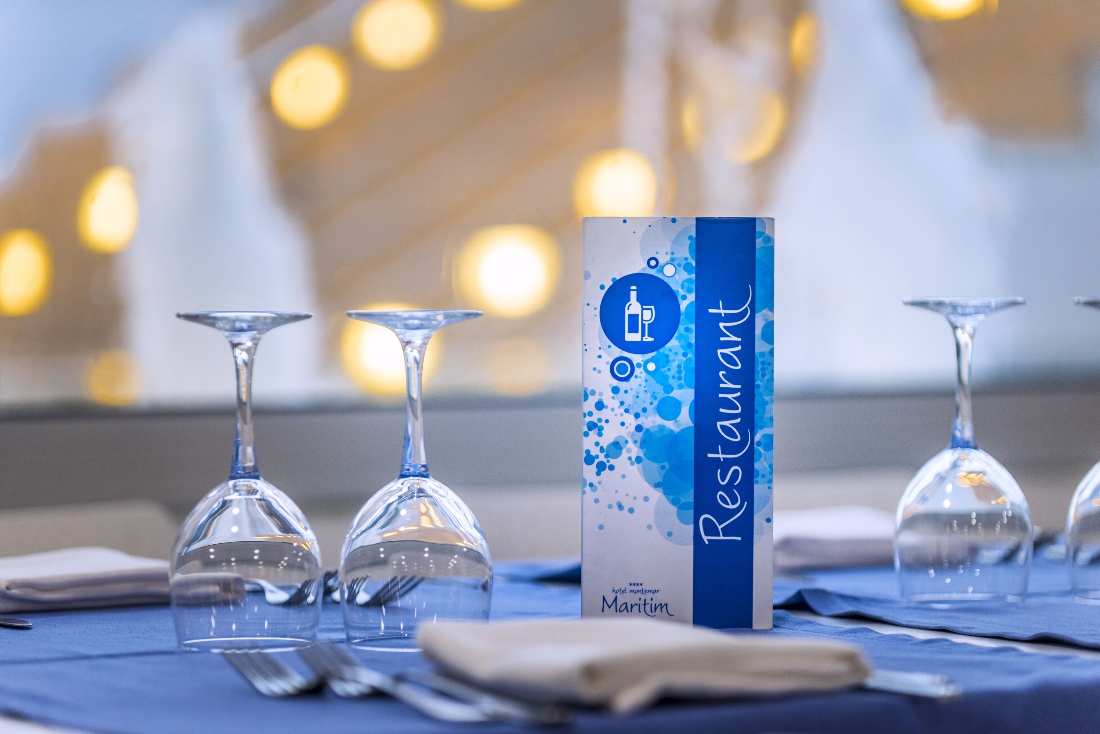 A table set with wine glasses and a menu box labeled "Restaurant Maritim."