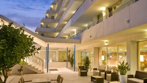 Un hôtel à plusieurs étages doté d’un vaste espace extérieur aménagé en terrasse, d’un escalier et d’une façade en verre.