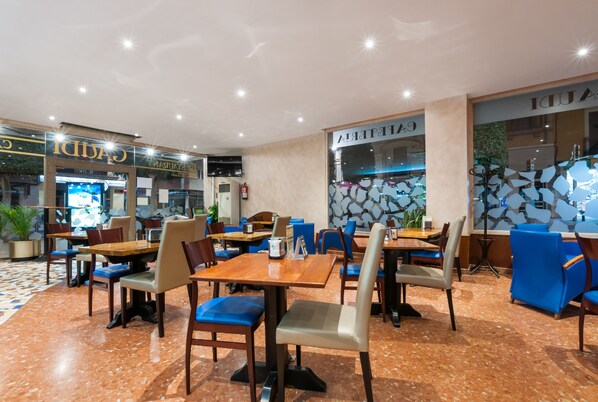 A spacious restaurant with multiple tables and chairs, a tiled floor, and a modern interior design. - Hotel Gaudí (Reus)