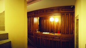 Una escalera con barandilla de madera y un panel de pared de madera, un espejo y una lámpara.