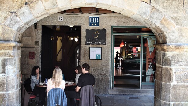 Un arco de piedra que da acceso a la entrada de un hotel, con un cartel que indica Hotel Airas Nunes.