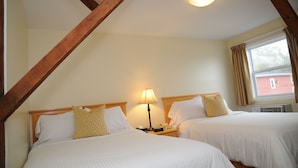 Een kamer met twee bedden, een nachtkastje met een lamp en een raam met gordijnen.