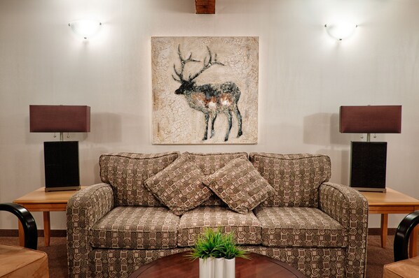 A living room with a patterned sofa, two side tables with lamps, and a wall-mounted artwork of an elk.