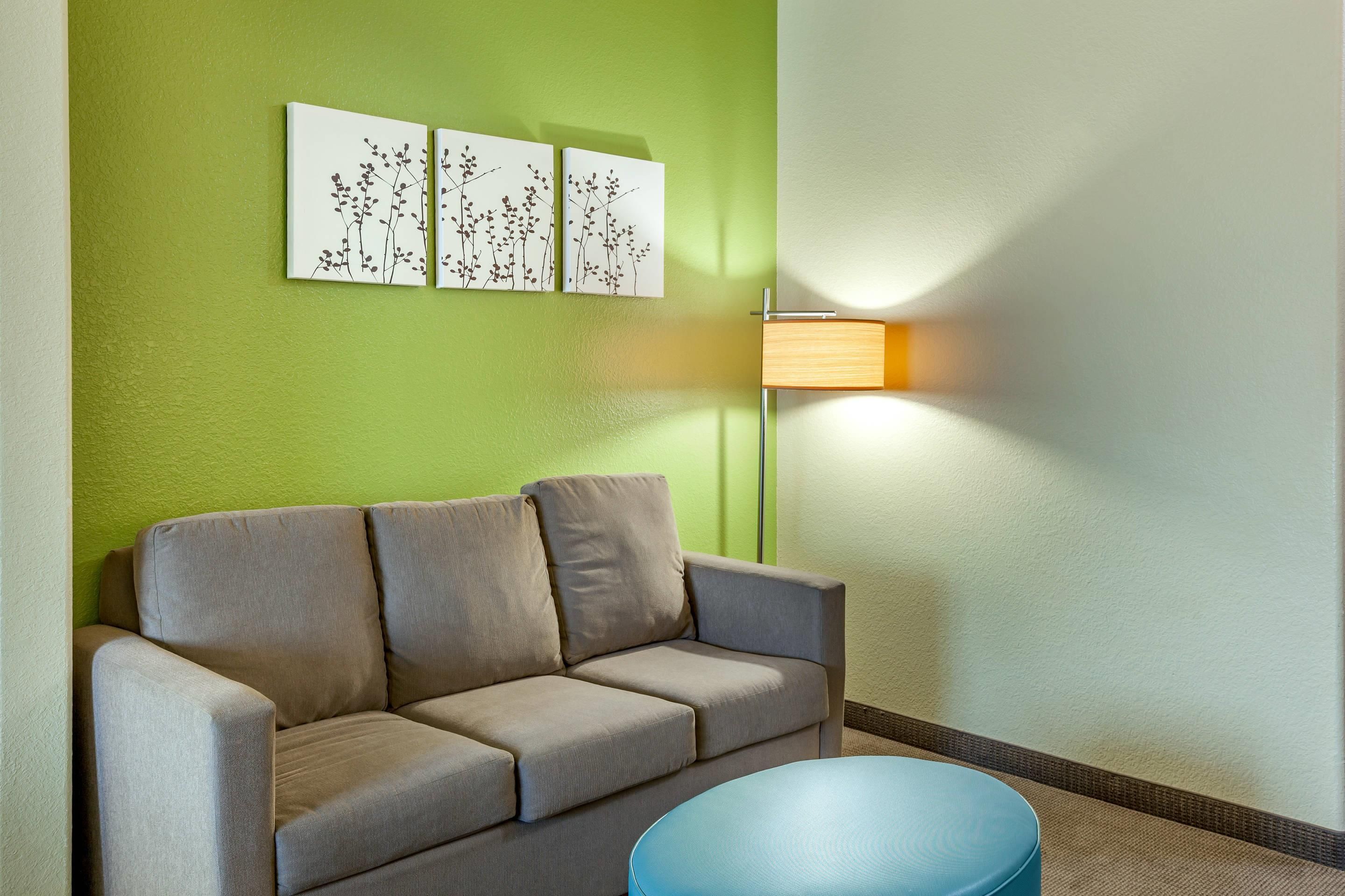 A room with a sofa, a round table, and wall-mounted artwork.