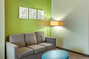 A room with a sofa, a round table, and wall-mounted artwork. - Sleep Inn & Suites Hewitt - South Waco (Hewitt)