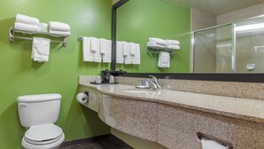 Un baño con pared verde, inodoro blanco, lavamanos de granito y varios toalleros.