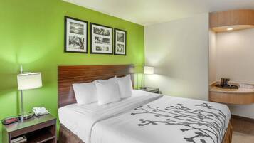 A hotel room with a bed, a nightstand, a lamp, a phone, and a wall with framed pictures.