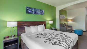 A hotel room with a bed, nightstand, lamp, and a painting on the wall.