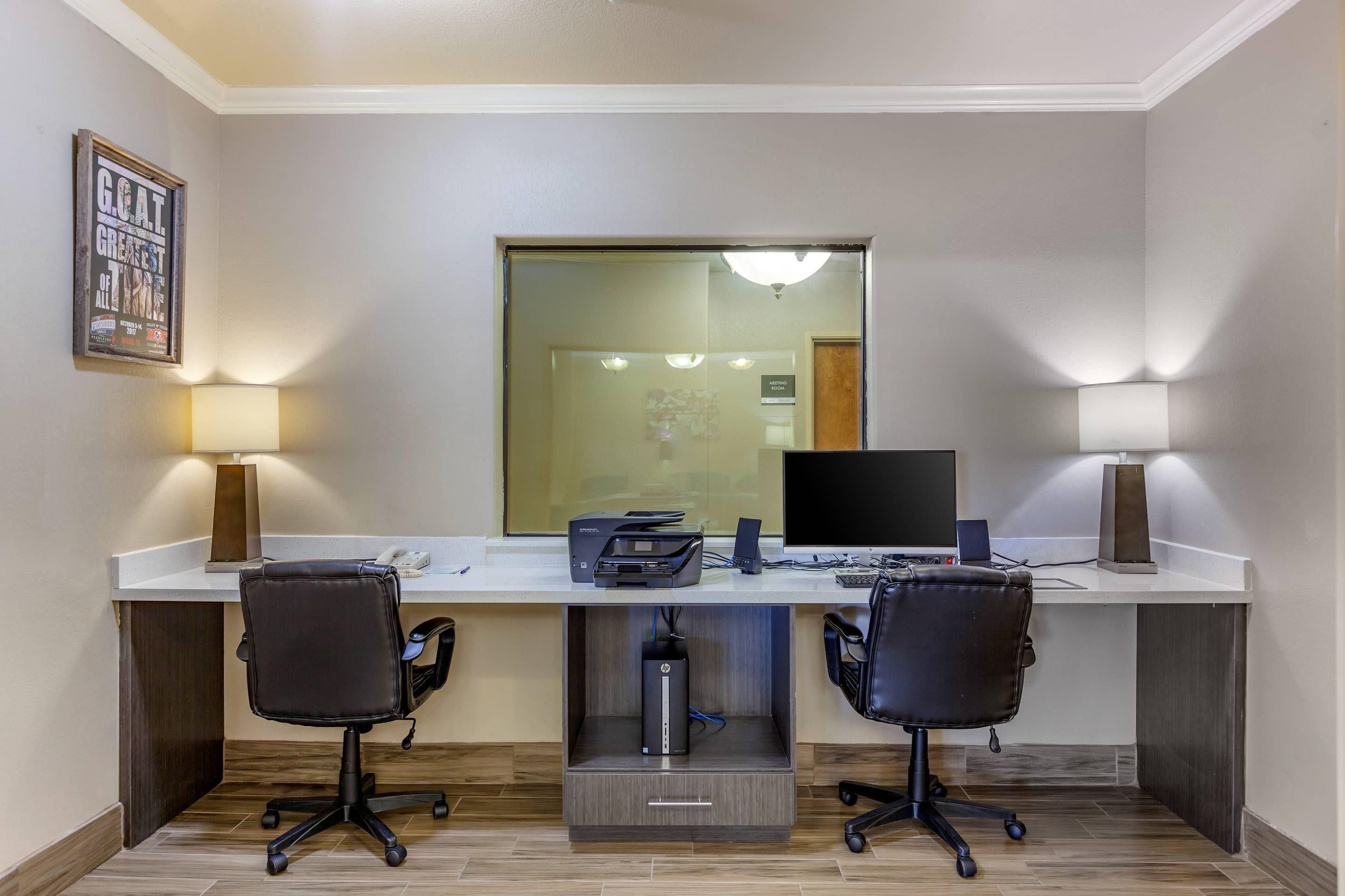 A modern office space with a desk, two chairs, a computer, a printer, and a large mirror.