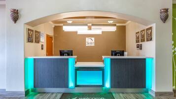 A reception desk with a 'Welcome' mat, framed awards, and a sign for 'Sleep Inn & Suites.'