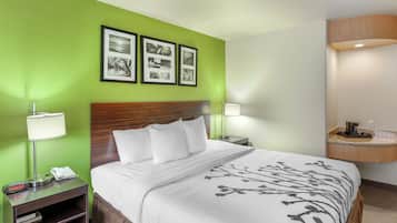 Een hotelkamer met een bed, een nachtkastje met een lamp, een telefoon en lijstjes met foto's aan de muur.