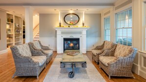 A living room with wicker furniture, a fireplace, and a staircase. - Chatham Wayside Inn (Chatham)