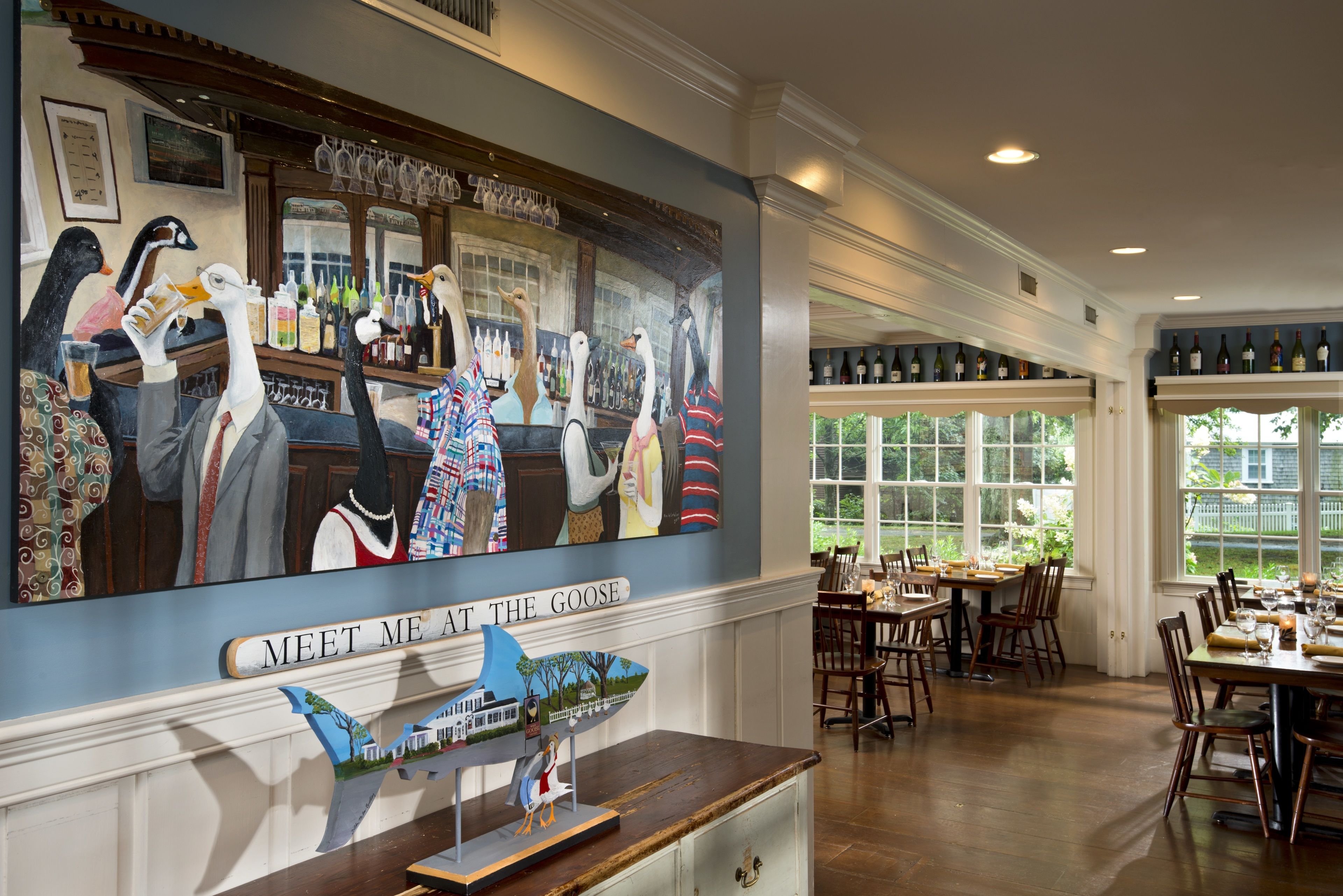 A restaurant interior with a mural of geese, a bar area, and a dining space with tables and chairs.