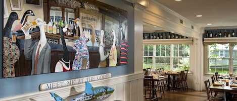 A restaurant interior with a mural of geese, a bar area, and a dining space with tables and chairs.