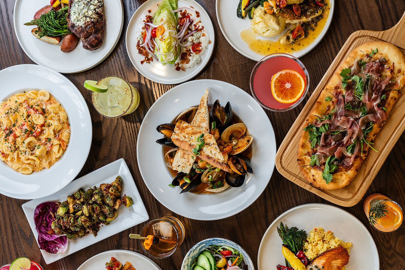 A variety of dishes including seafood, pasta, and a pizza, suggesting a diverse dining selection.