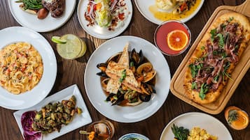 A variety of dishes including seafood, pasta, and a pizza, suggesting a diverse dining selection.