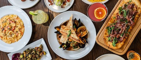 A variety of dishes including seafood, pasta, and a pizza, suggesting a diverse dining selection.