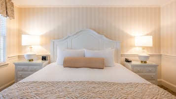 A neatly made bed with a patterned bedspread, two bedside lamps, and a nightstand with a phone and a lamp.