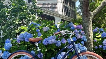 A bicycle parked in front of a house with a porch and a tree.
