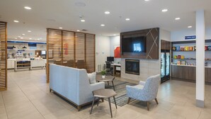 A modern interior with a seating area, a fireplace, a kitchen, and a snack bar. - Holiday Inn Express & Suites Marquette by IHG (Marquette)