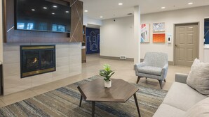 A modern lobby with a fireplace, a flat-screen TV, and a seating area with a sofa and armchair. - Holiday Inn Express & Suites Marquette by IHG (Marquette)