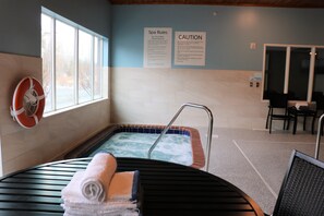 A spa area with a hot tub, towels, and safety signs. - Holiday Inn Express & Suites Marquette by IHG (Marquette)
