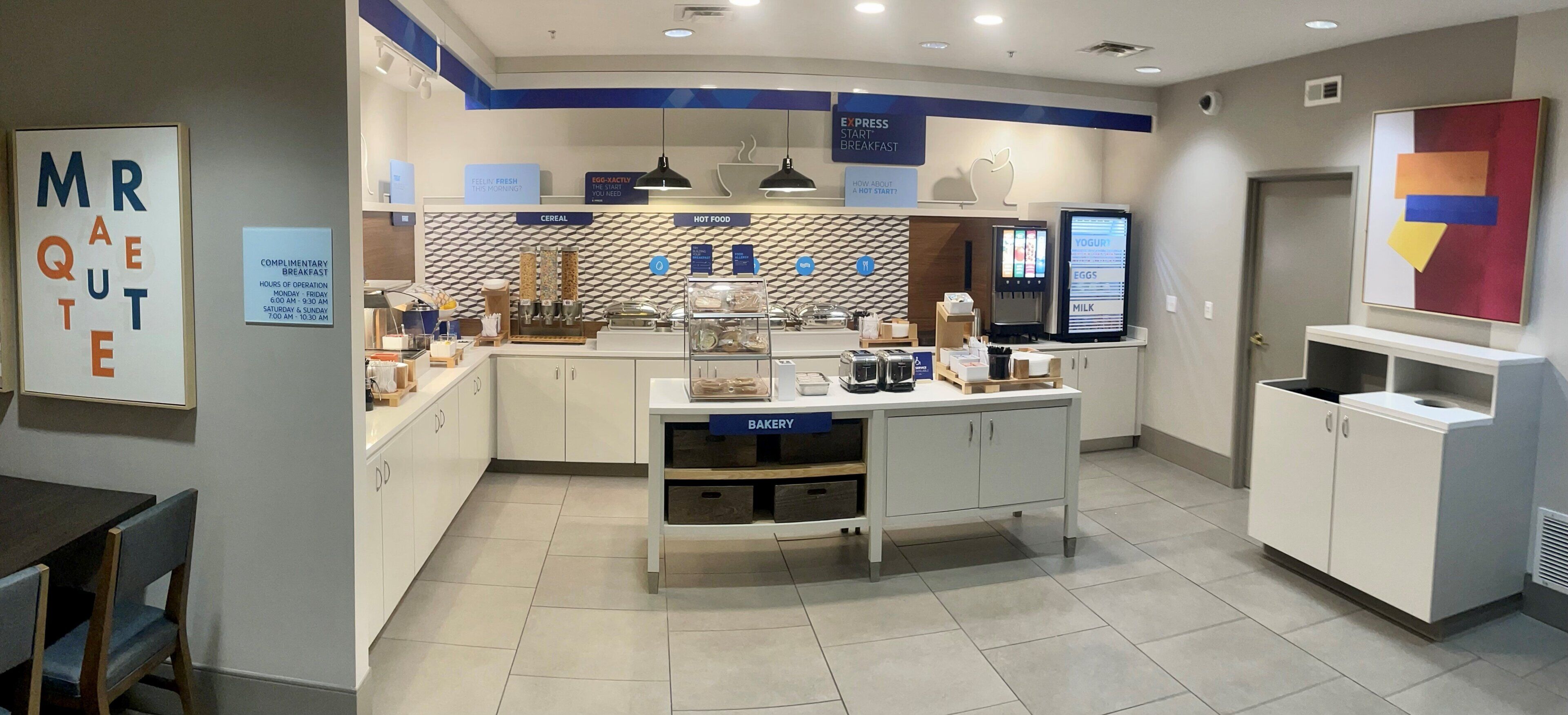 A breakfast area with a counter, display screens, and various food items.