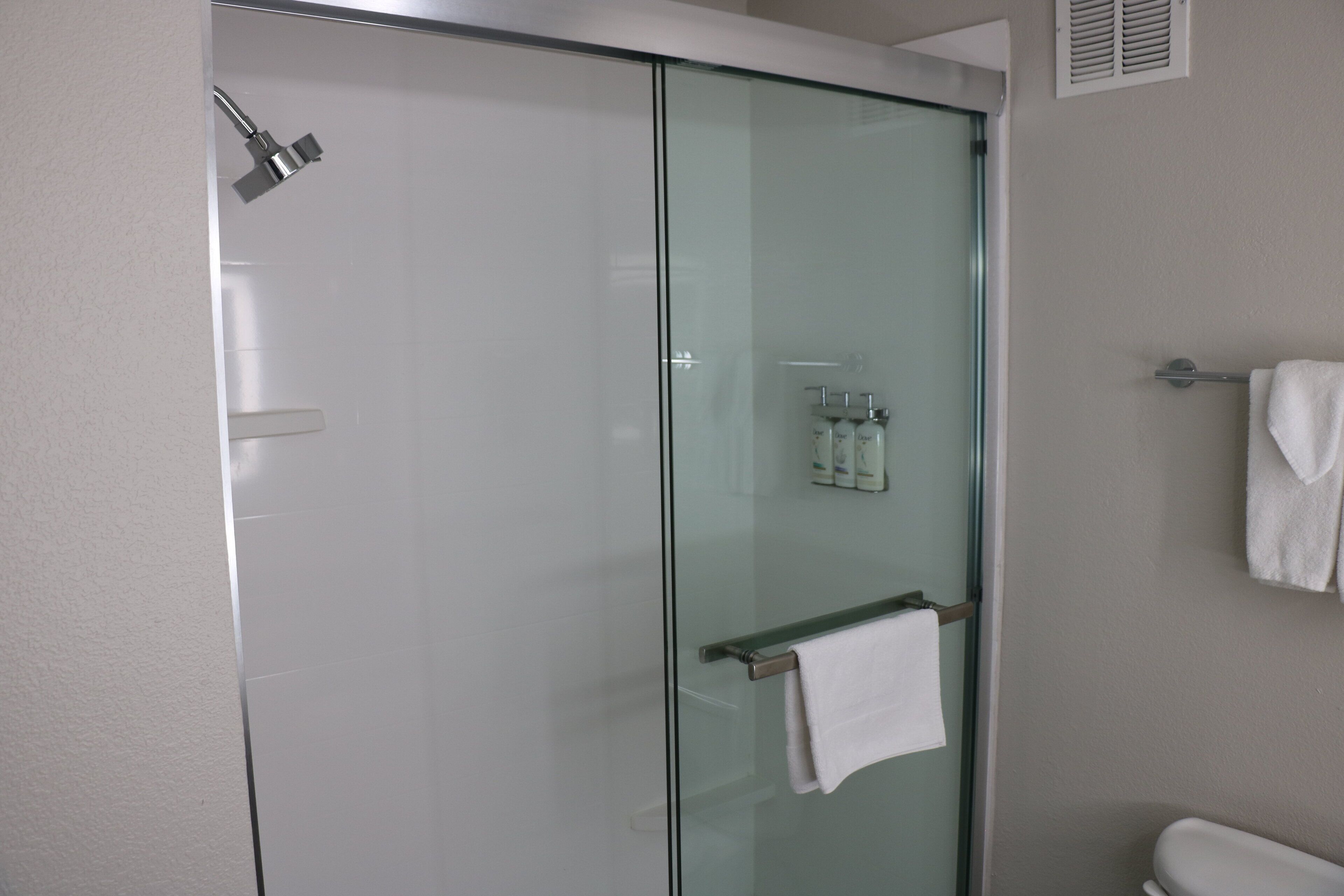 A modern bathroom with a glass-enclosed shower, a toilet, and a towel rack.