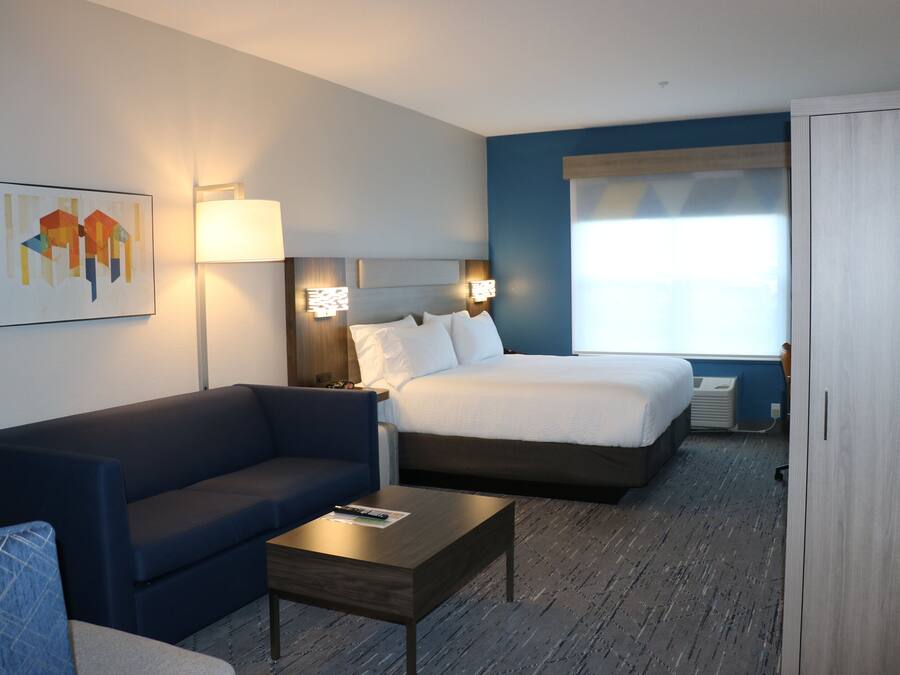 Una habitación de hotel con una cama, un sofá, una mesita de café y un cuadro en la pared.