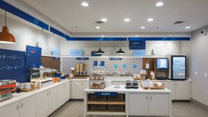 A modern breakfast area with labeled sections for cereal, hot food, and bakery, featuring a clean and organized layout. - Holiday Inn Express & Suites Marquette by IHG (Marquette)