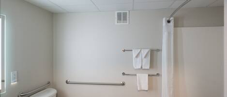 Un baño con inodoro, lavamanos, toallero y cortina de ducha.