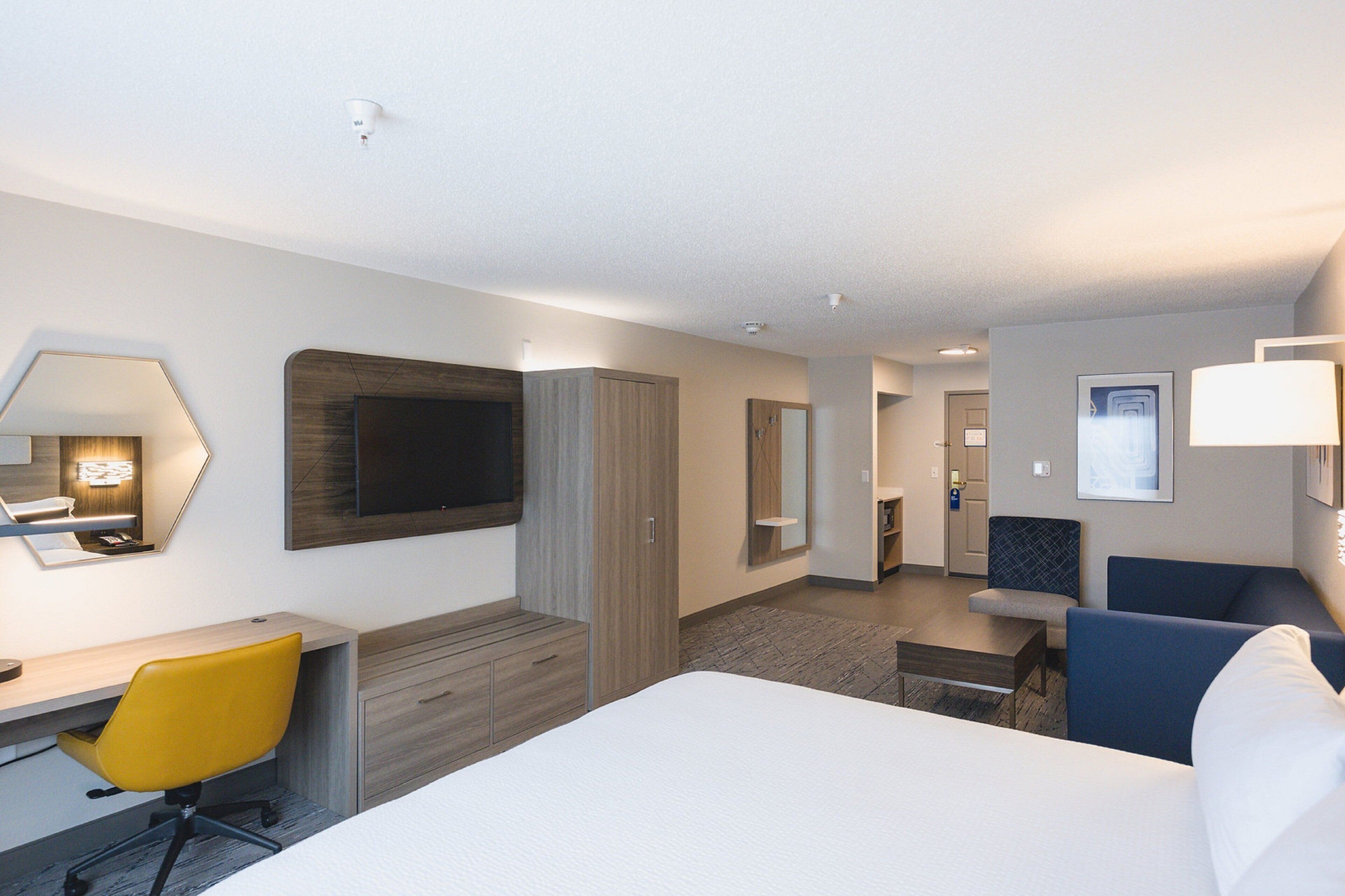 A hotel room with a bed, a desk, a chair, a TV, and a bathroom.