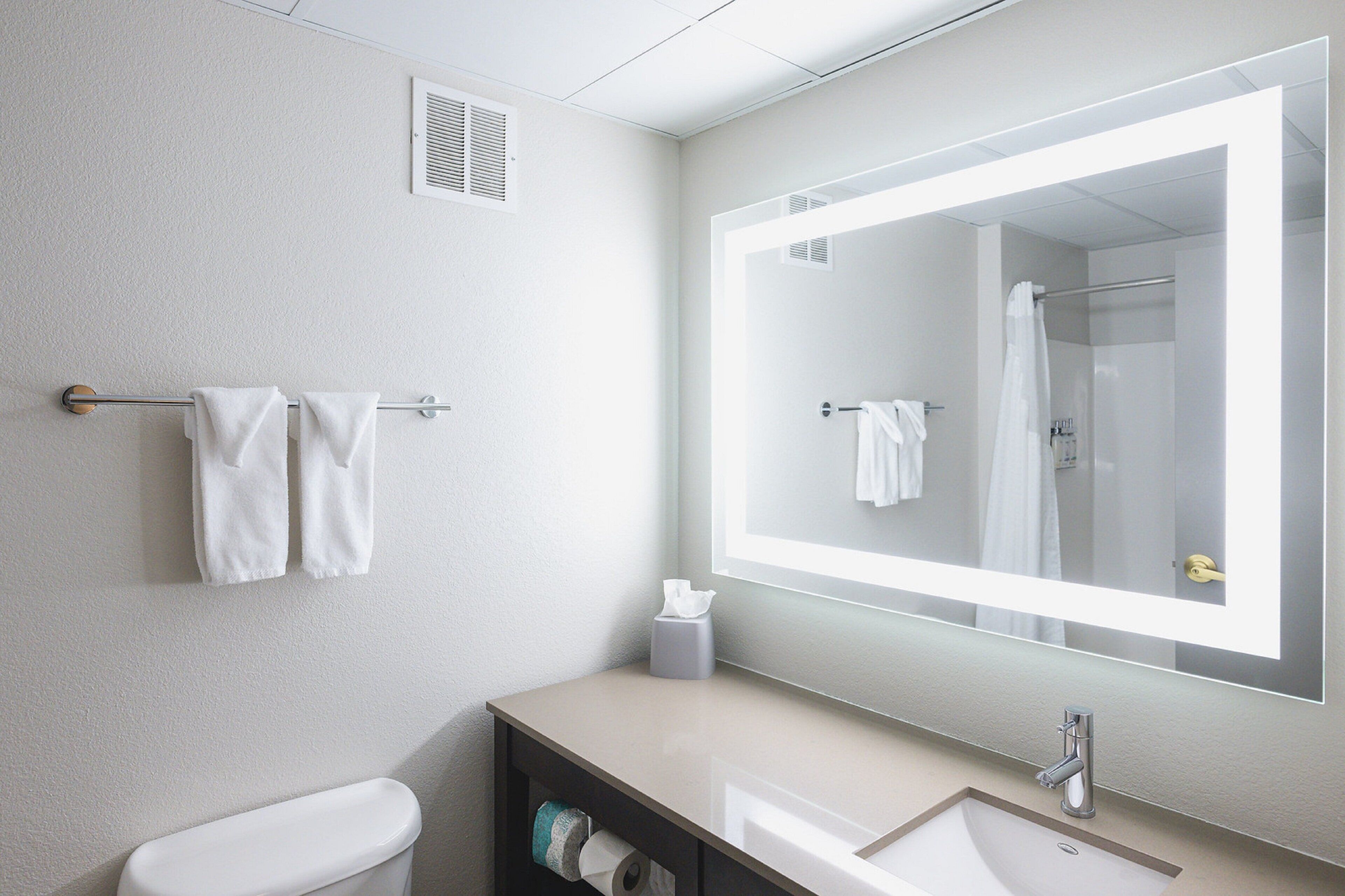 Een moderne badkamer met toilet, wastafel en grote spiegel.