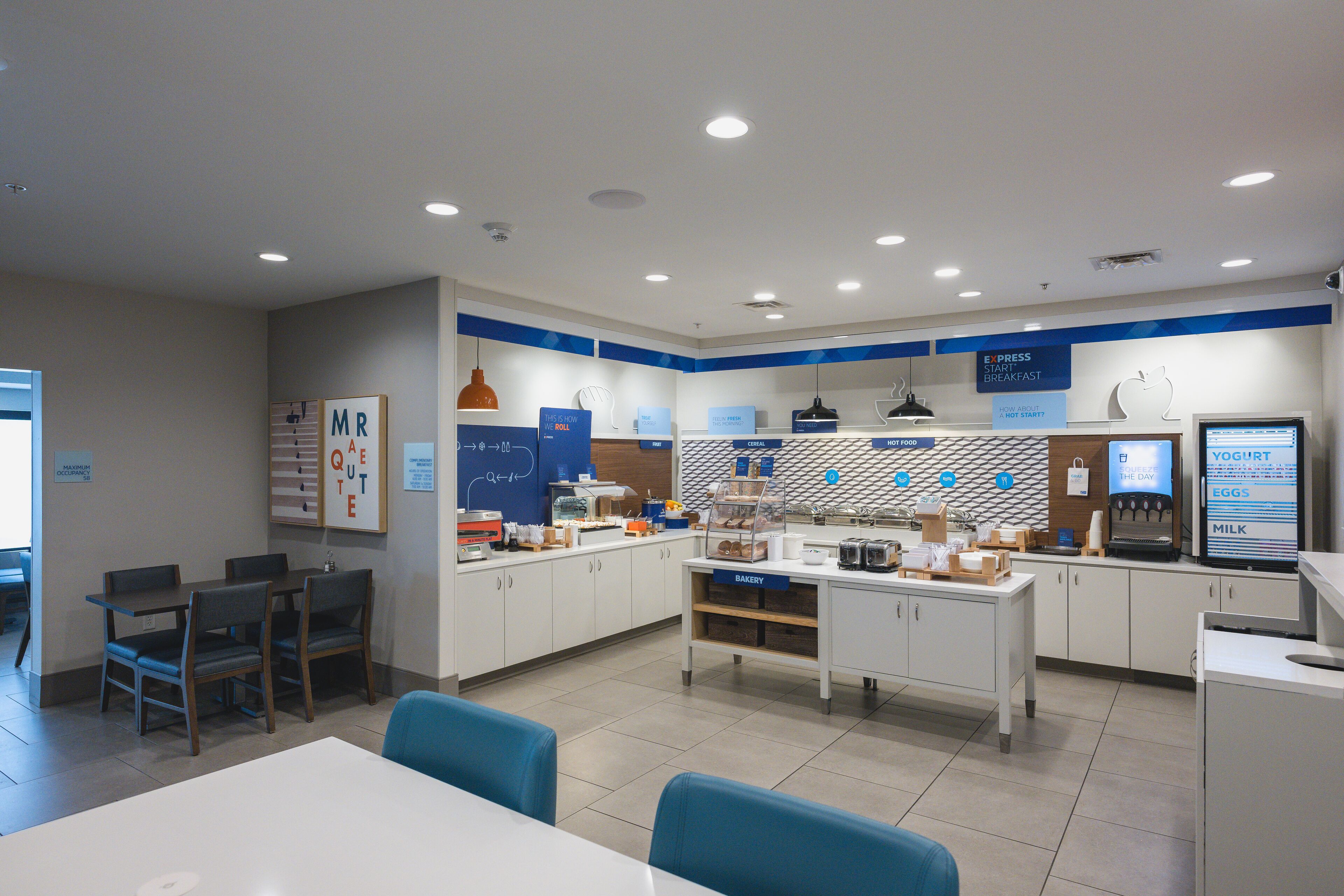 A modern breakfast area with a counter, seating, and various food display options.