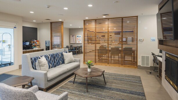 A modern living room with a sofa, coffee table, and a fireplace. - Holiday Inn Express & Suites Marquette by IHG (Marquette)