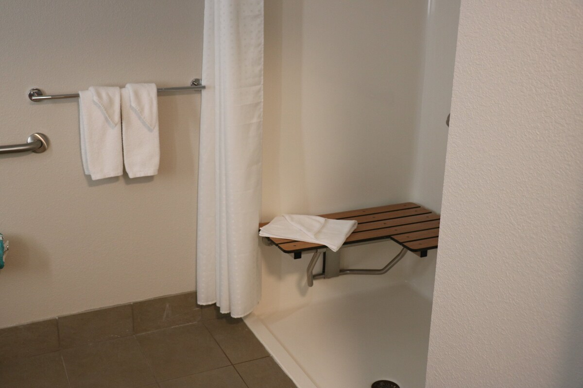 Une salle de bain avec une douche, un banc et un porte-serviettes.
