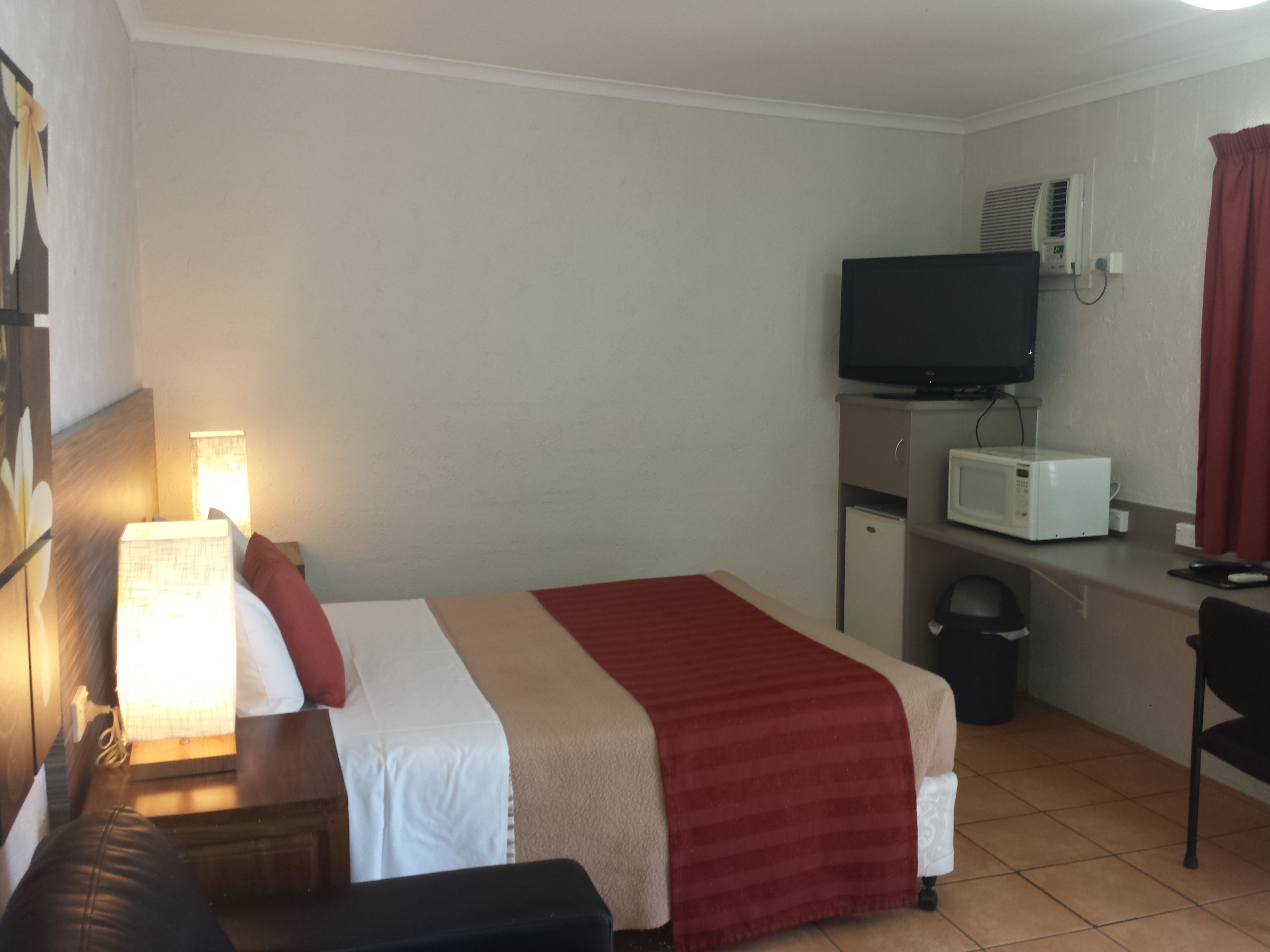 Une chambre d’hôtel équipée d’un lit, d’un bureau avec un ordinateur, d’une télévision et d’un four à micro-ondes.
