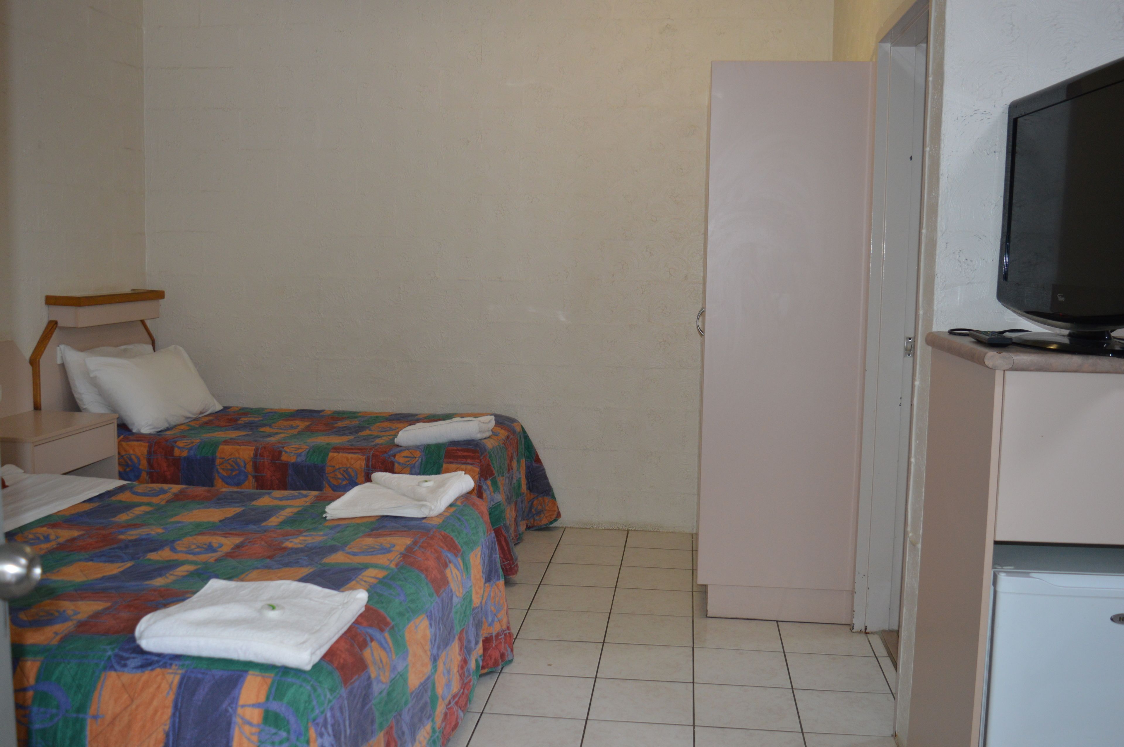 A hotel room with two beds, a television, and a small refrigerator.