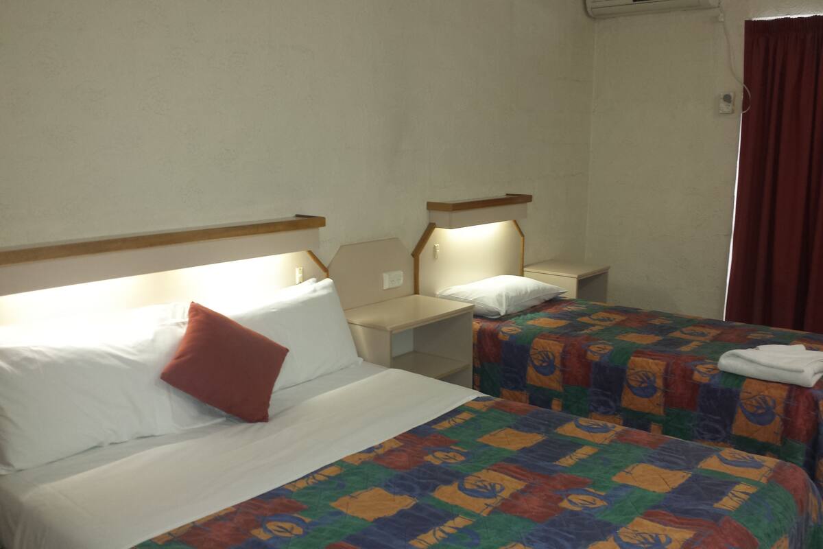 A hotel room with two beds, a desk, and a nightstand.