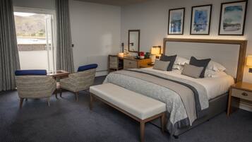 Habitación de hotel con una cama grande, un escritorio, una silla y vistas al exterior.