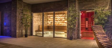 A modern lobby with a glass partition, a wooden staircase, and potted plants.