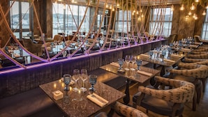 A restaurant with a long counter, hanging lights, and a view of the city. - Quay Hotel and Spa (Conwy)